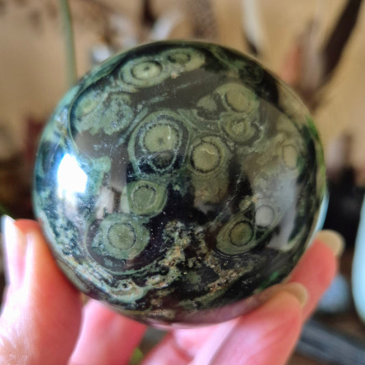 green tones crystal sphere held in a hand
