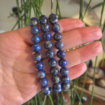Hand holding a stack of blue beaded bracelets with a blurred background
