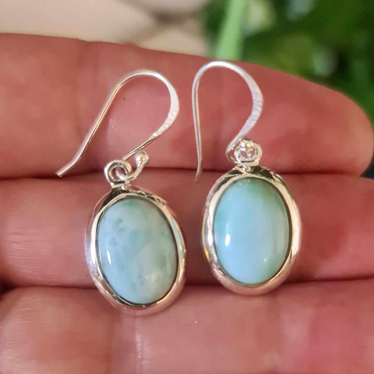 A pair of silver-colored Larimar earrings with a round, blue and white stone set in a sterling silver setting.