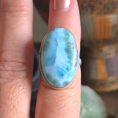 Ring with a large turquoise stone on a finger against a blurred background