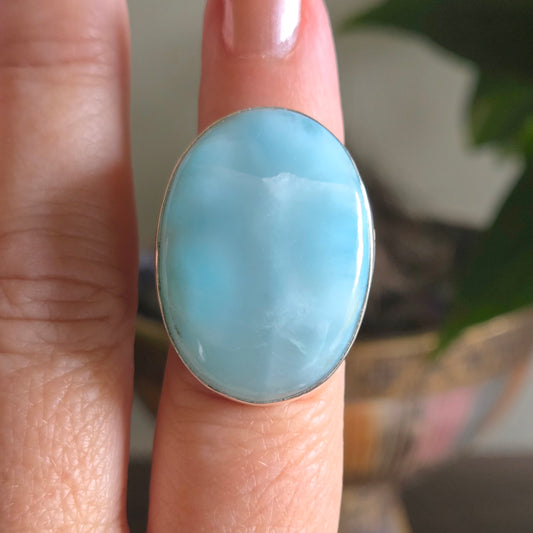 Ring with a large blue stone on a finger against a blurred background