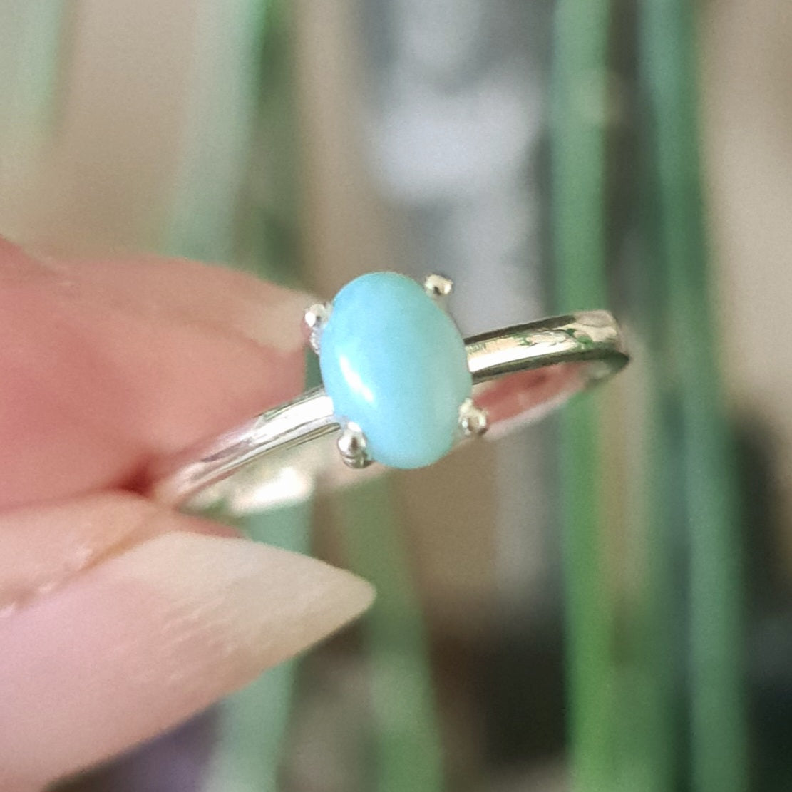 A sterling silver ring with a blue Larimar stone set on a finger.