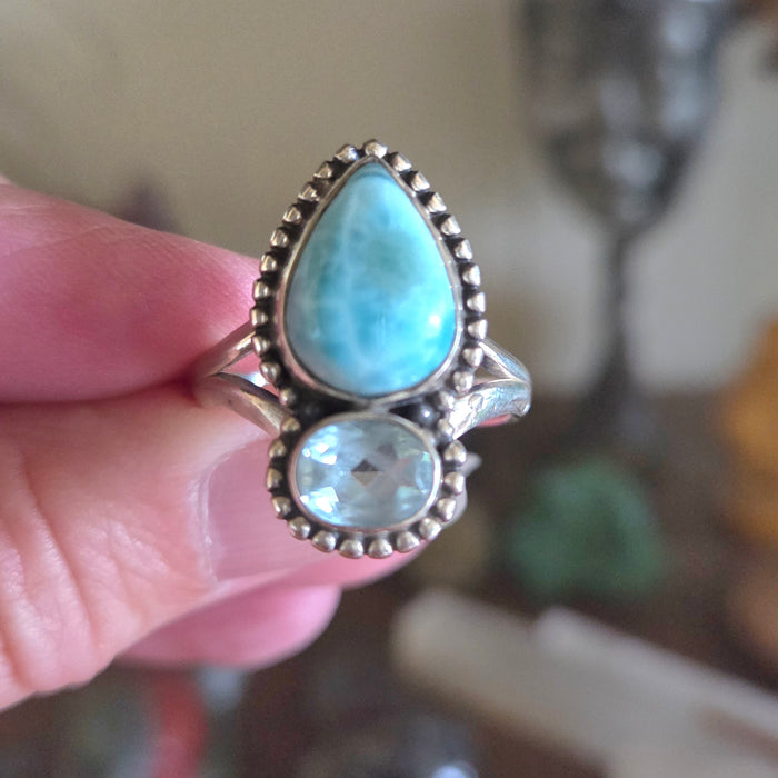 Ring with turquoise stones held by a hand against a blurred background
