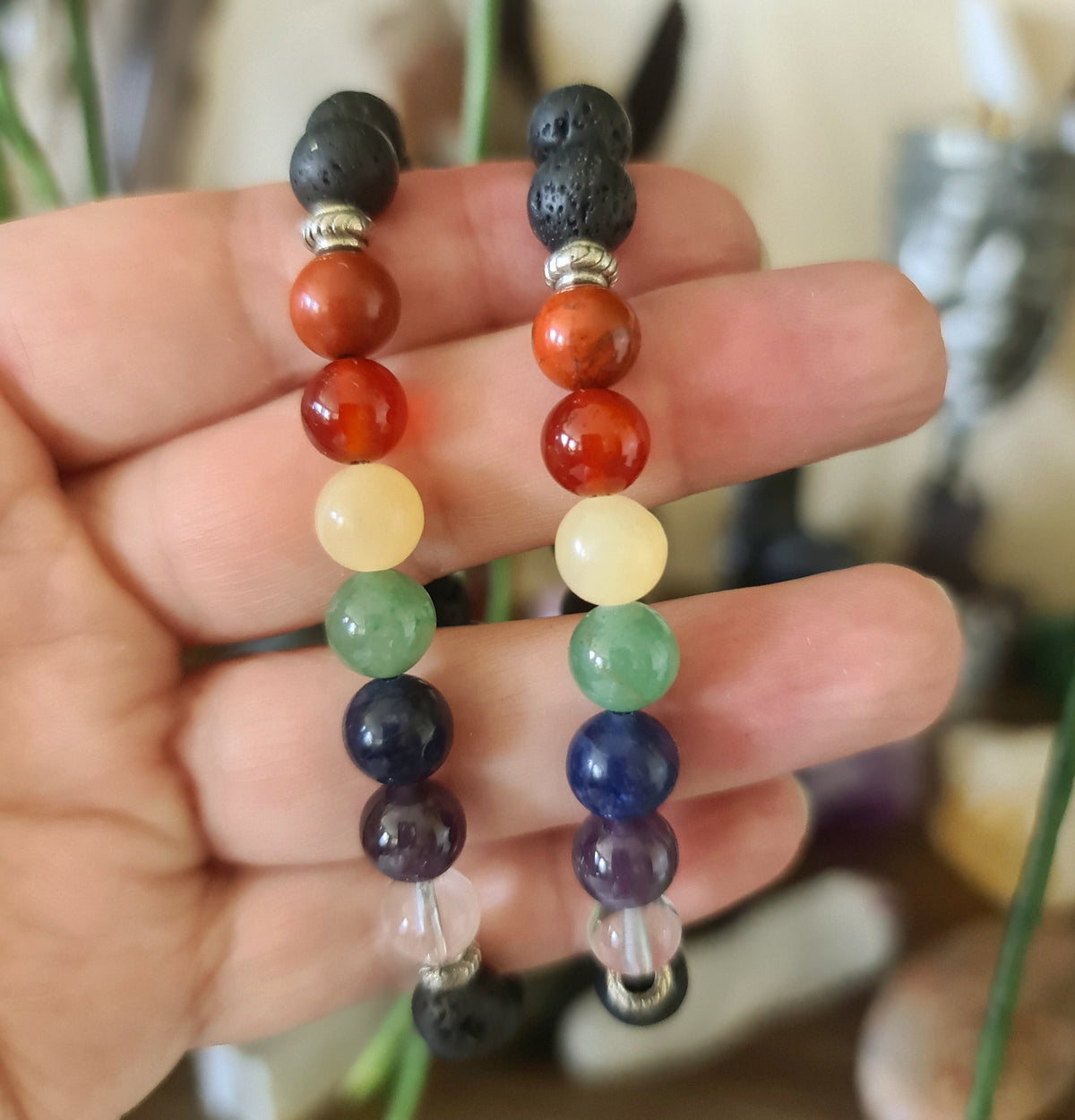 A hand holding a multicolored beaded bracelet with gold-colored spacers, designed for aromatherapy.