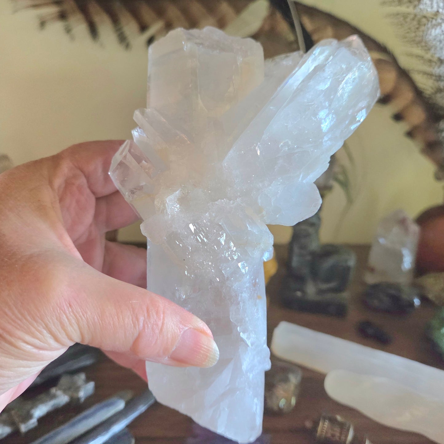 Hand holding a large crystal formation with more crystals in the background