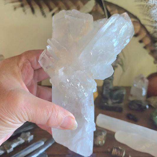 Hand holding a large crystal formation with more crystals in the background