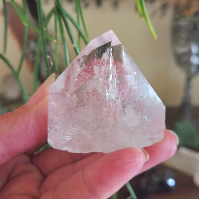 Clear crystal held in a hand with a blurred background