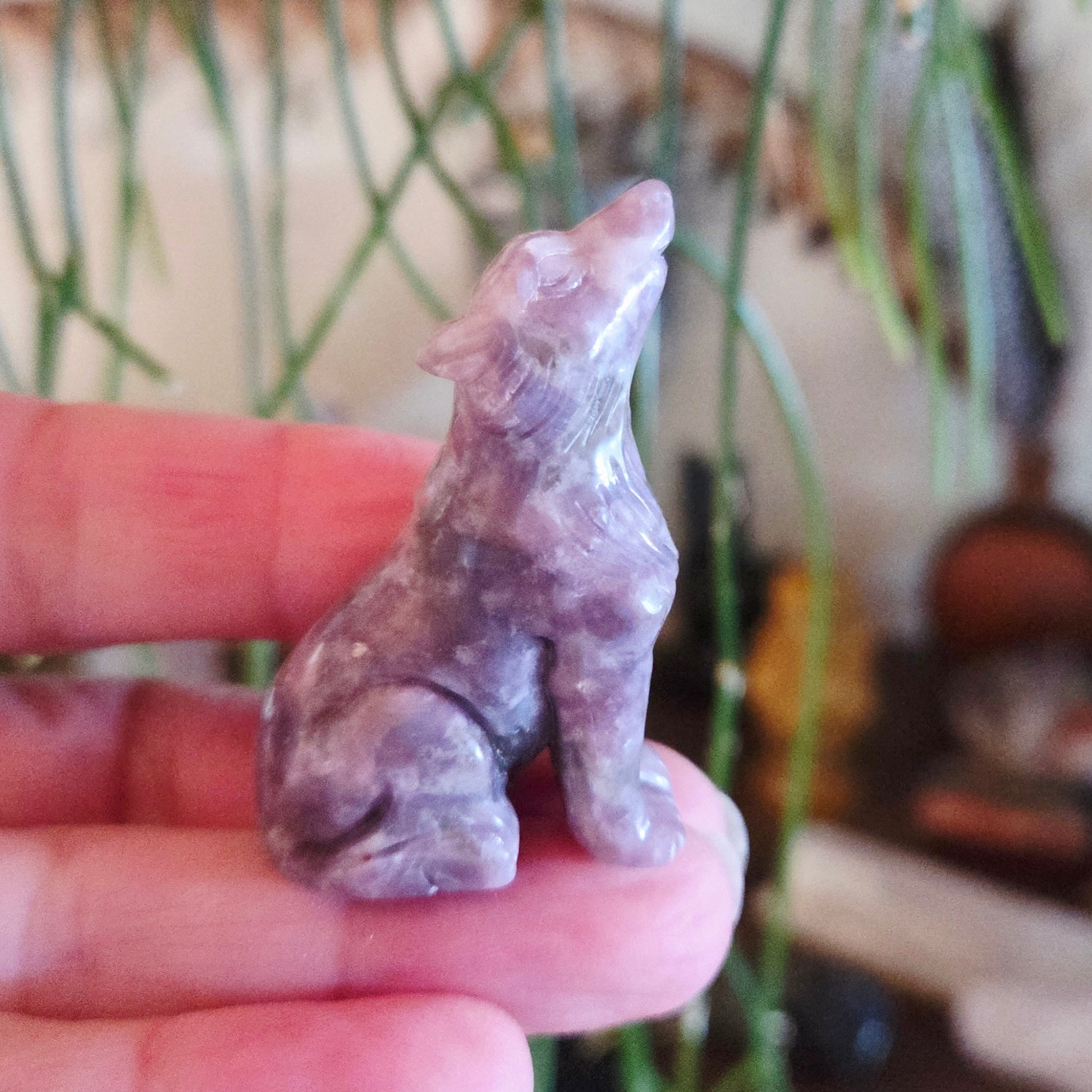 Hand holding a small purple stone animal figurine with a blurred background