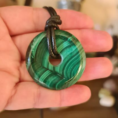A green malachite donut-shaped pendant with a black leather cord necklace.