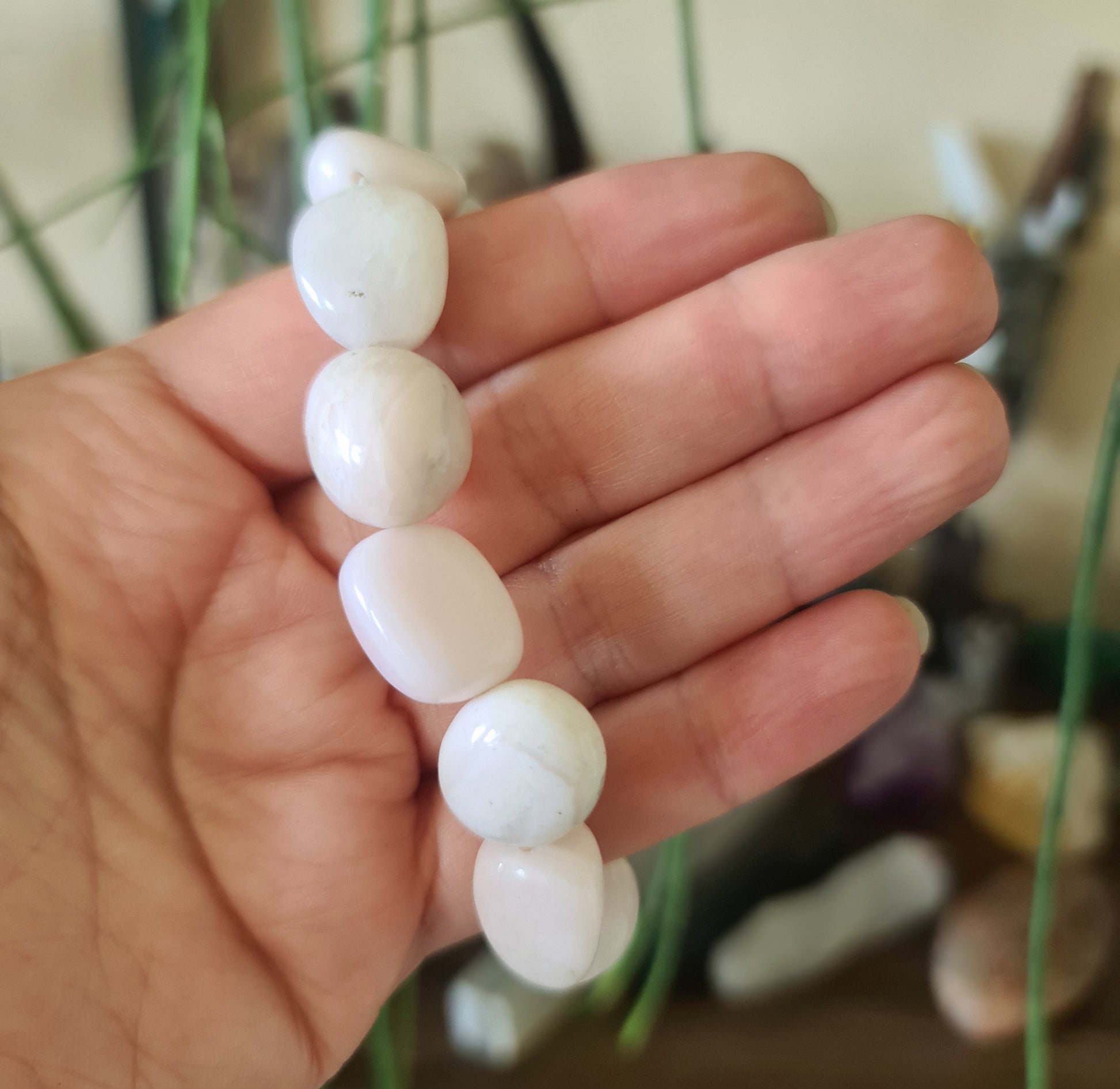 A hand holding a pink Mangano Calcite heart-shaped bracelet.