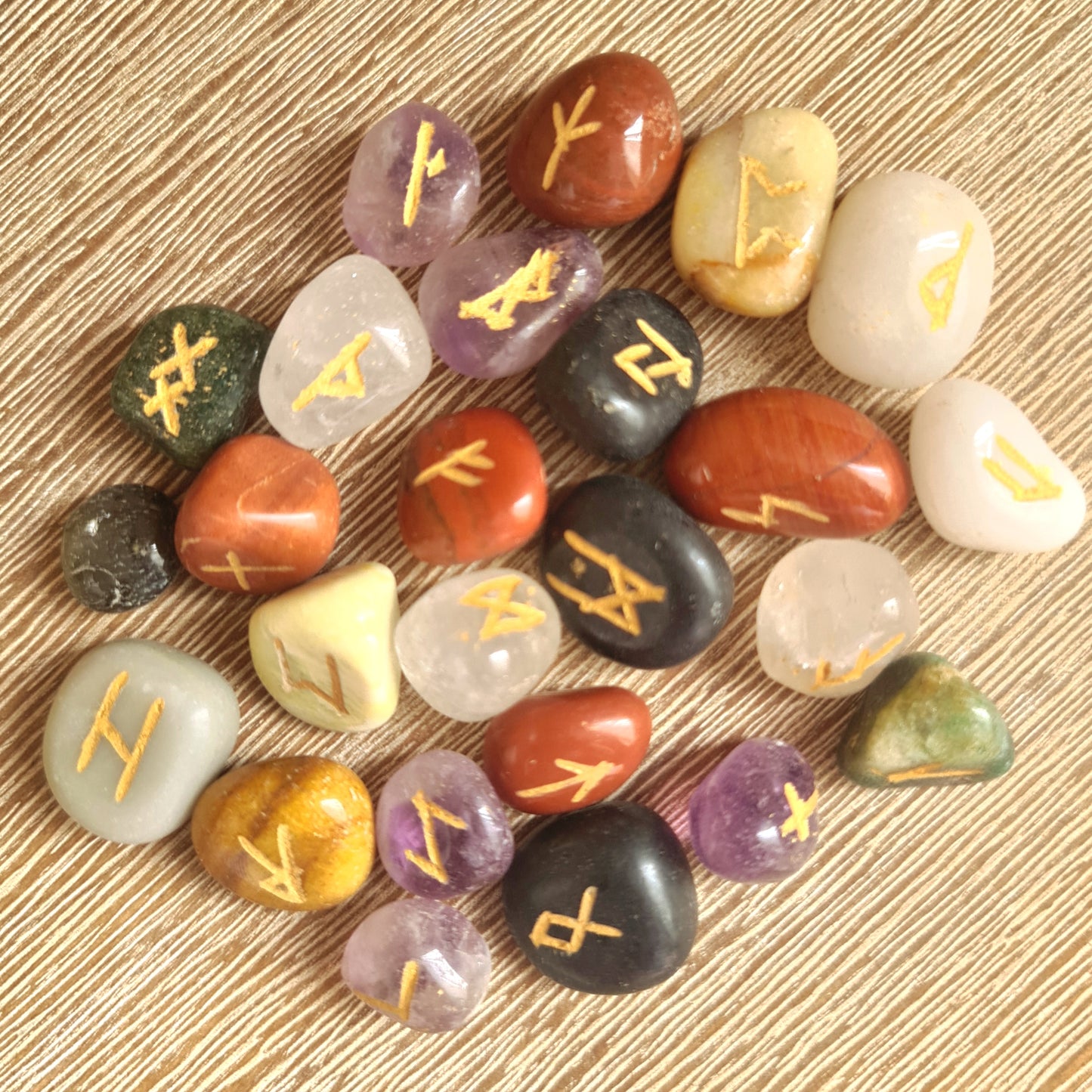 A collection of various colored stones with runic symbols inscribed on them, used for healing and spiritual purposes.