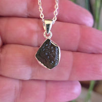 Necklace with a pendant held between fingers