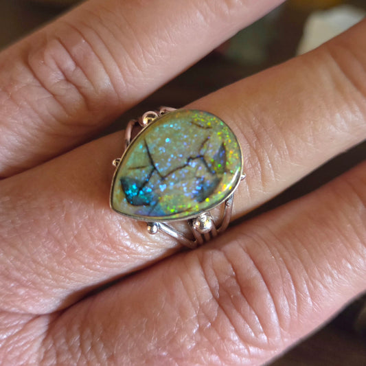 Ring with a large, colorful gemstone on a finger