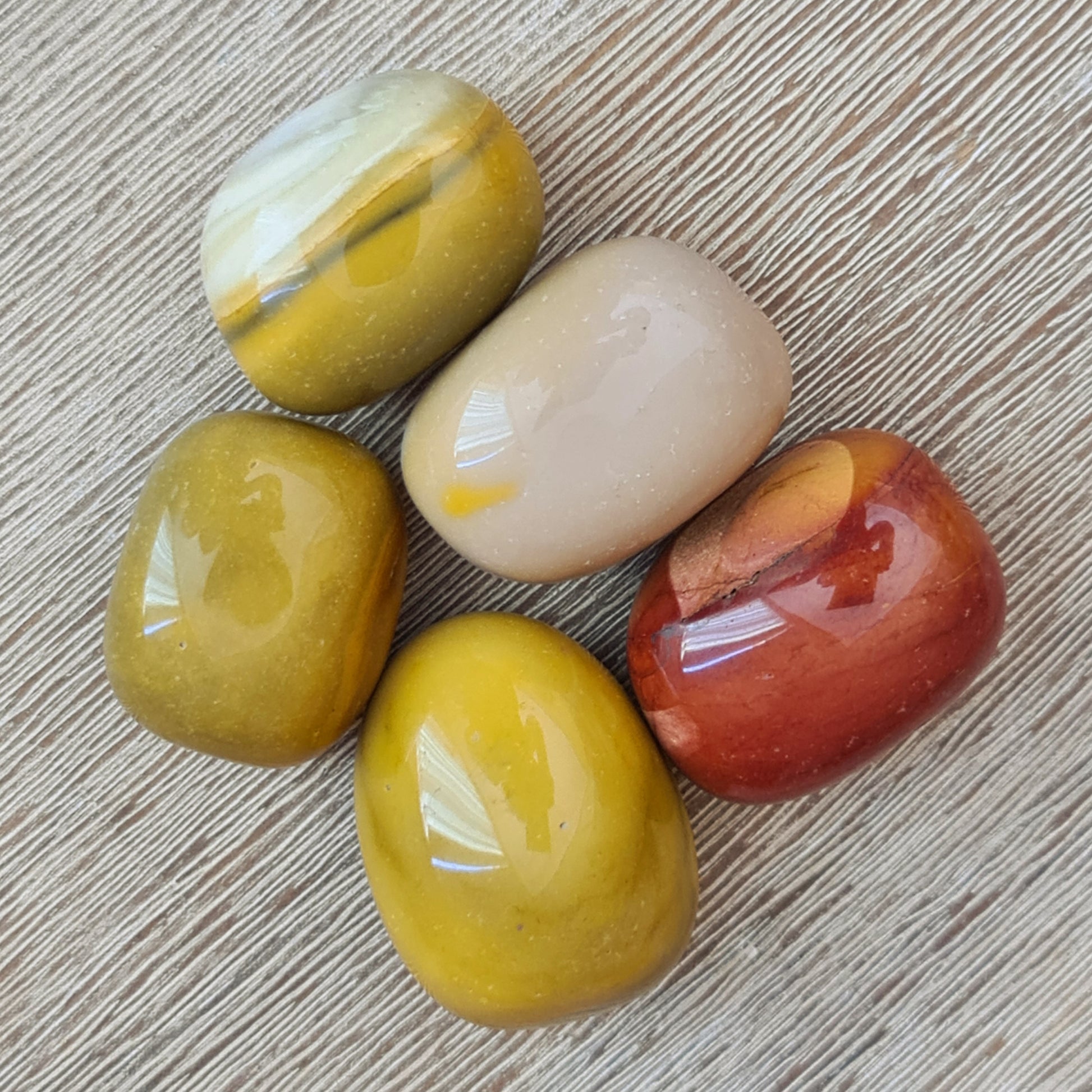 A collection of Mookaite Jasper Tumblers in various colors including yellow, beige, and red.