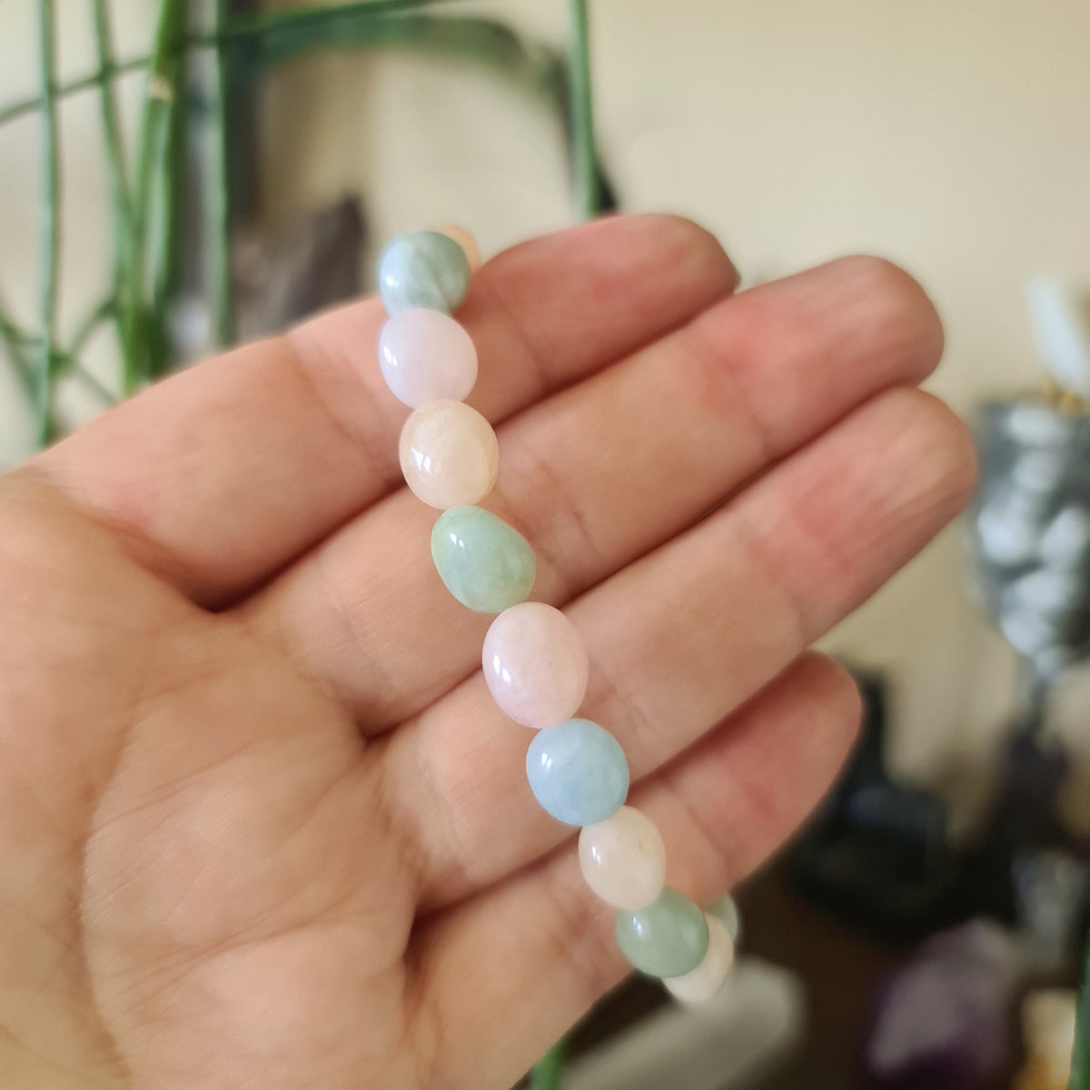 A Morganite bracelet with pink and blue translucent beads, held in a person's hand.