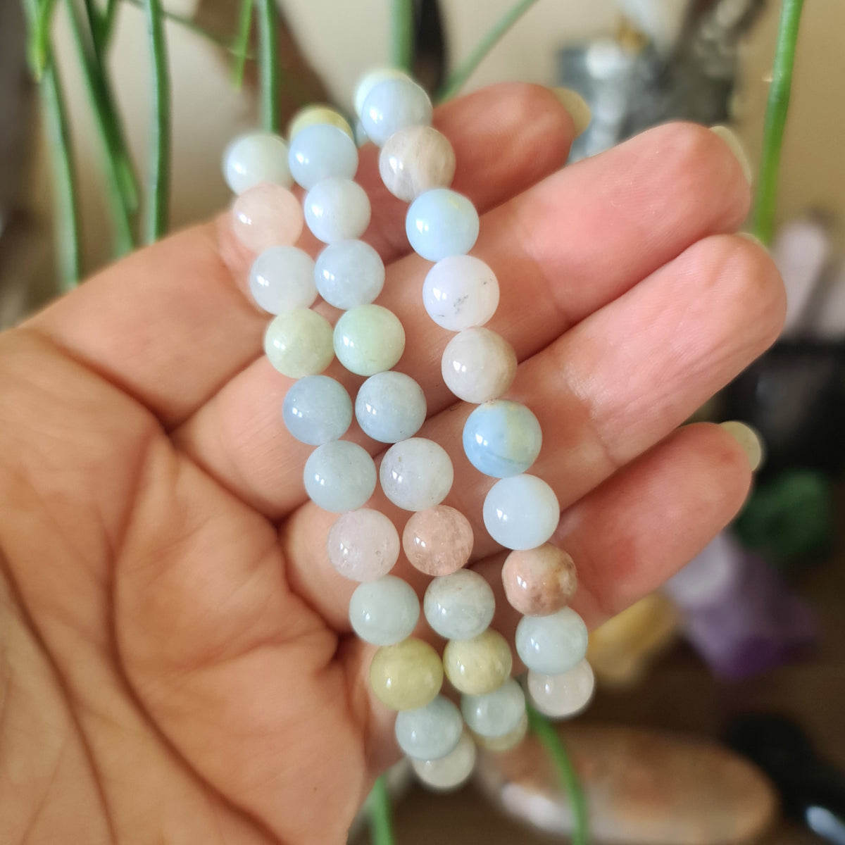 pastel blue, white and pink bracelets held in a hand