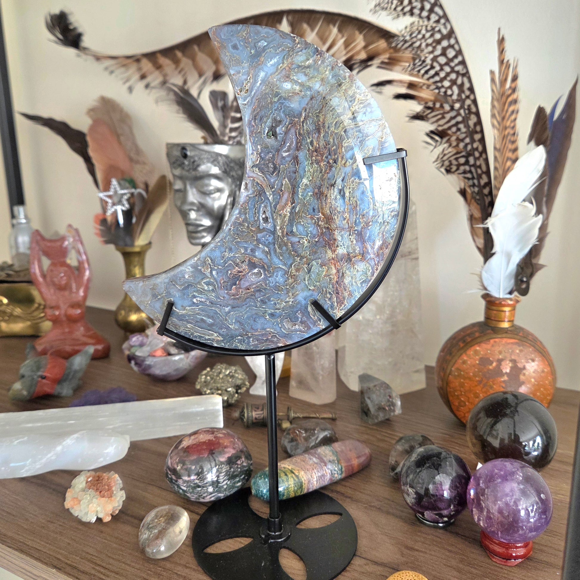 Decorative crystal ball on a stand with crystals and feathers in the background