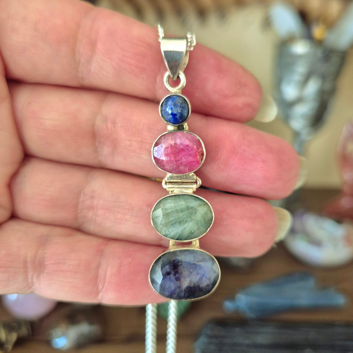 A sterling silver pendant with multiple faceted crystals including lapis lazuli, ruby, emerald, and sapphire.