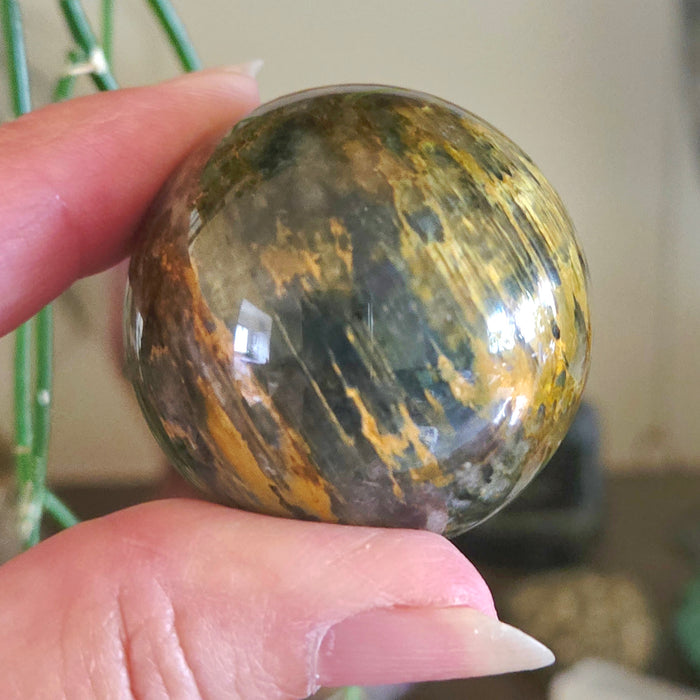 Hand holding a marbled stone sphere with a blurred background