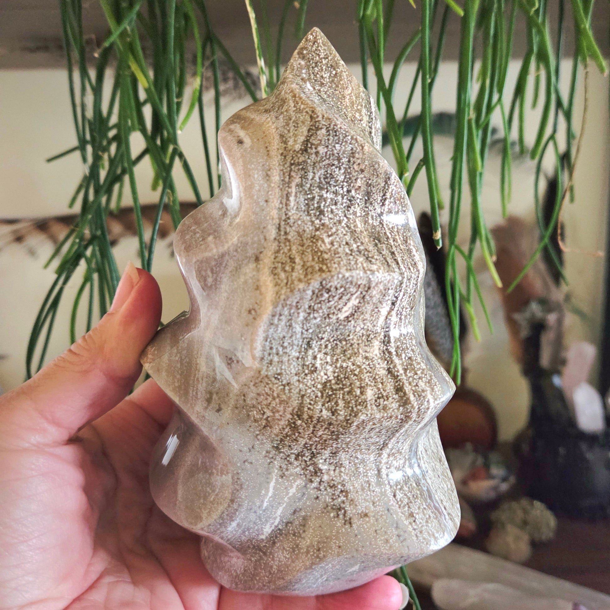 A hand holding a polished Ocean Jasper stone with a visible flame-like pattern.
