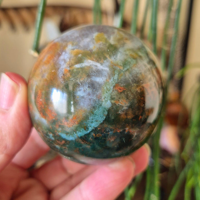 ocean jasper sphere held in a hand