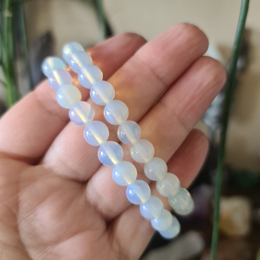A hand holding a series of blue and white opalite beads, typically used for crafting jewelry such as bracelets.