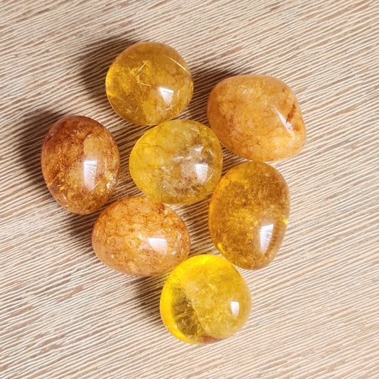 A collection of polished orange crackle quartz stones arranged on a wooden surface.