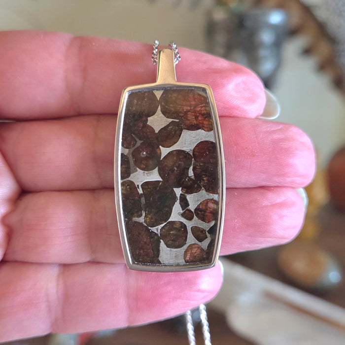 Gold pendant with embedded stones held in a hand
