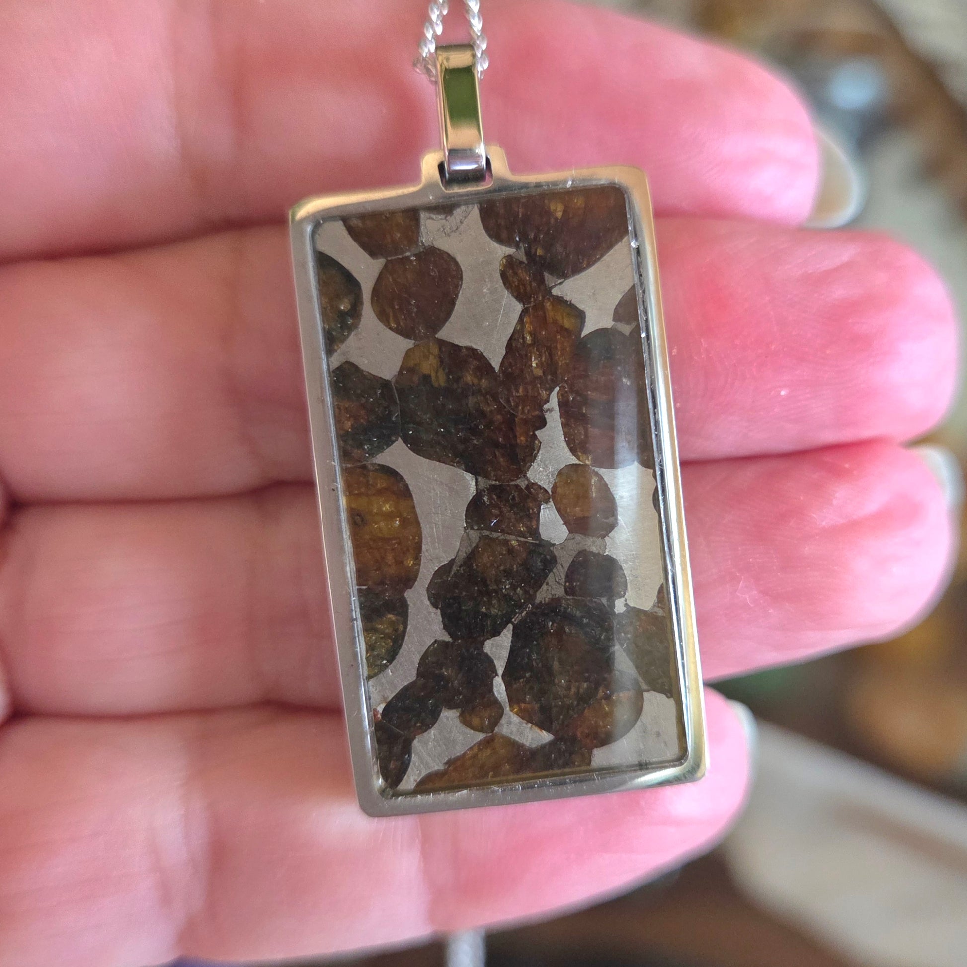 Rectangular pendant with stone inlay held in a hand