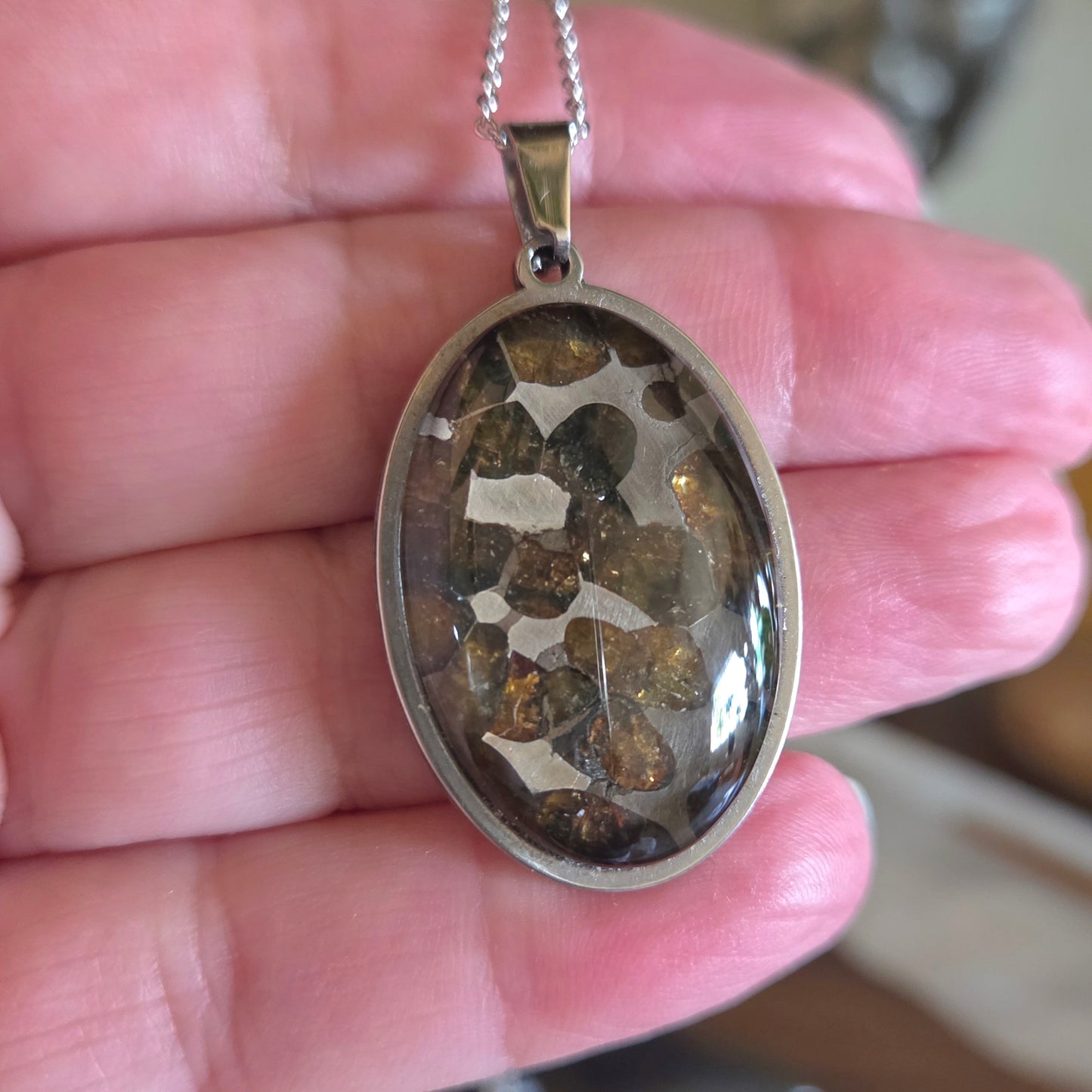 Oval-shaped pendant with embedded stones held in a hand
