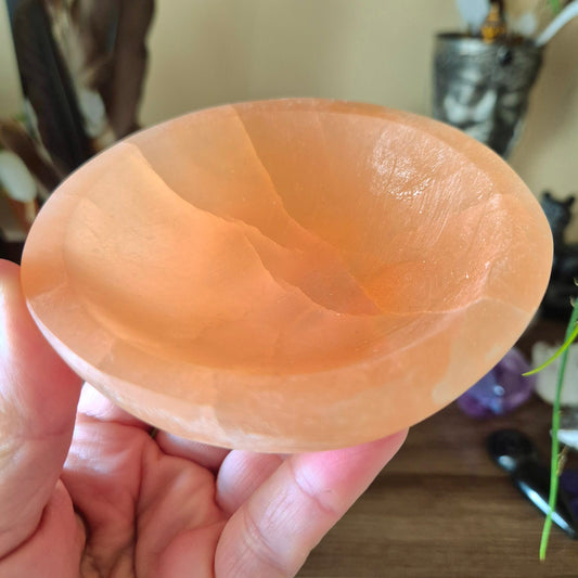 peach colour selenite bowl held in a hand