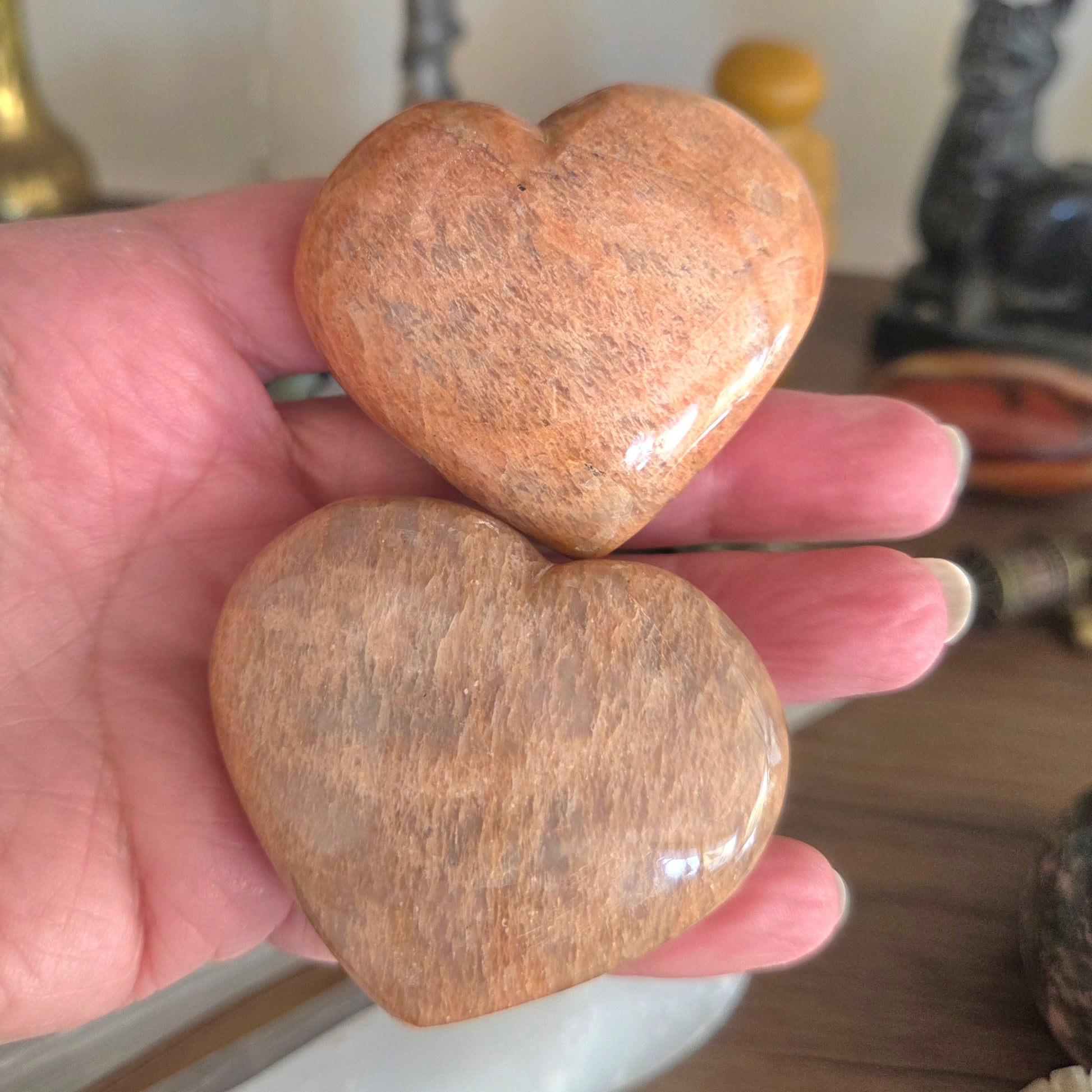 Two heart-shaped stones held in a hand with a blurred background