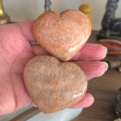 Two heart-shaped stones held in a hand with a blurred background