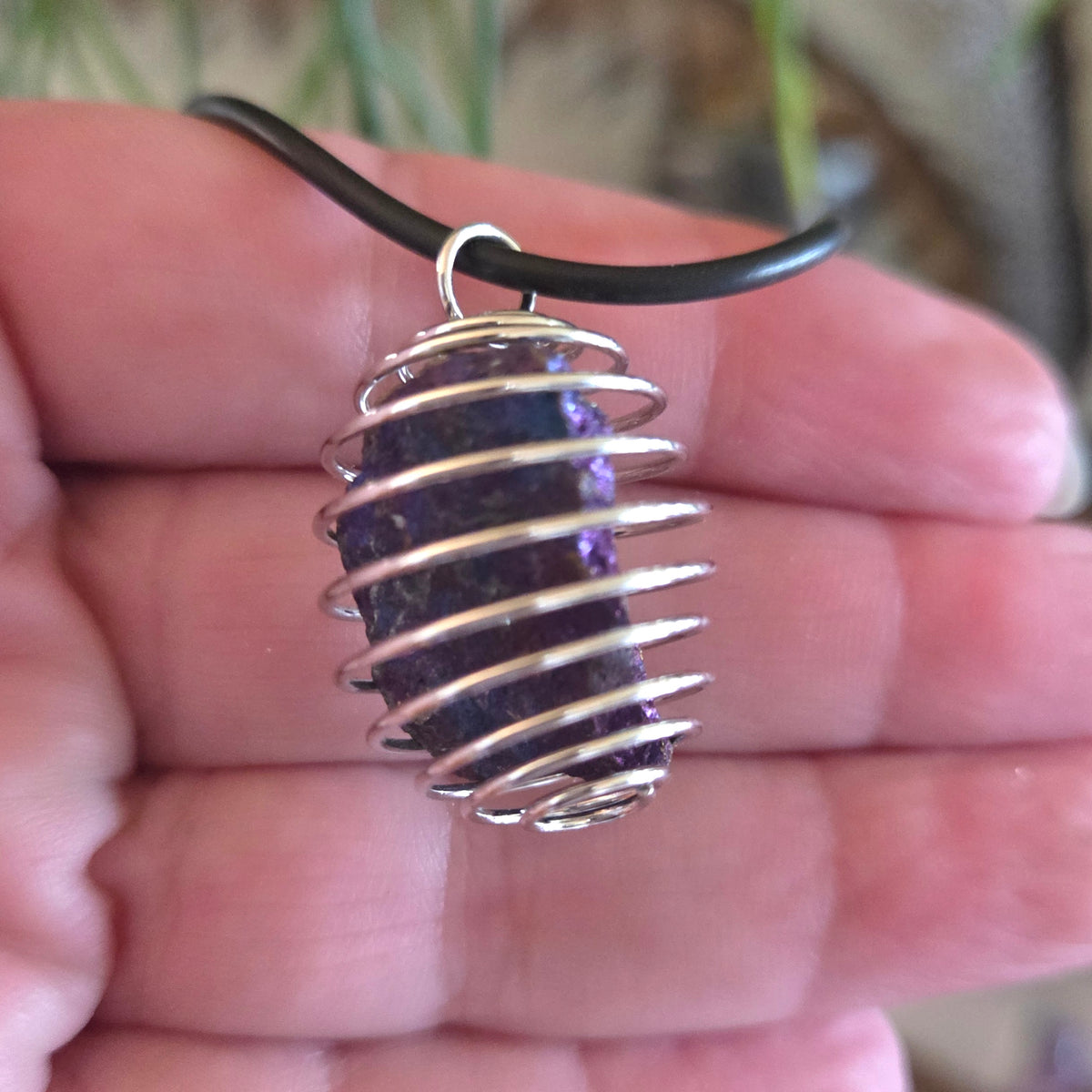 Peacock Ore pendant with silver wire wrapping held in a hand