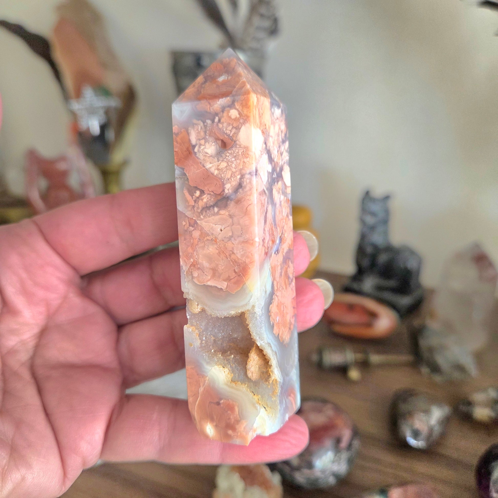 Hand holding a crystal with a blurred background of decorative items