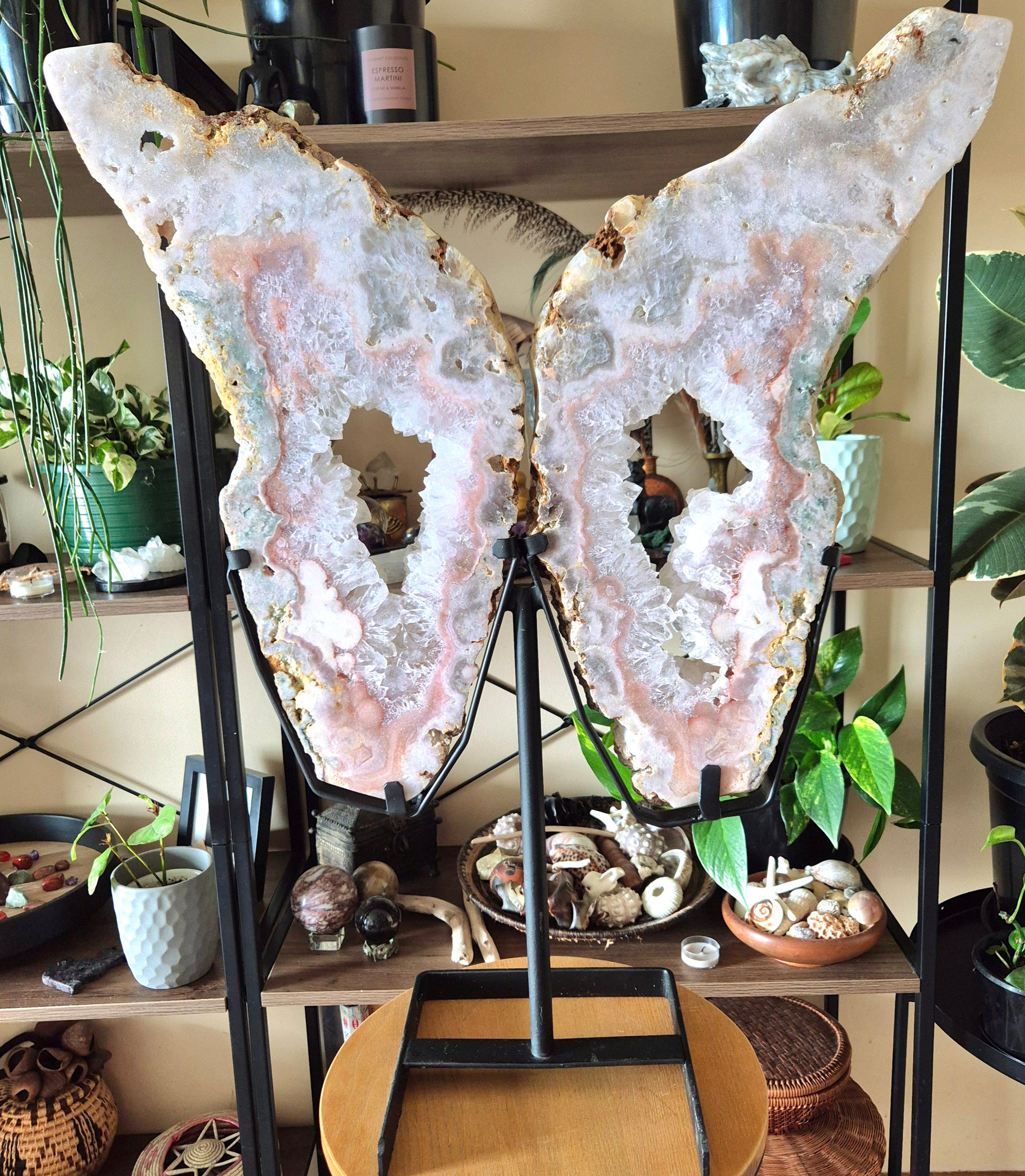 A pair of pink amethyst crystal figurines shaped like angel wings, displayed on a stand.
