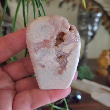Hand holding a white stone with brown markings against a blurred background