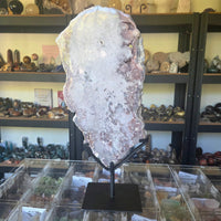 Large crystal on a stand in a store setting with shelves of various items in the background