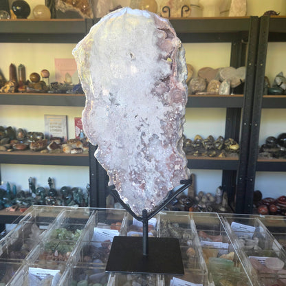 Large crystal on a stand in a store setting with shelves of various items in the background