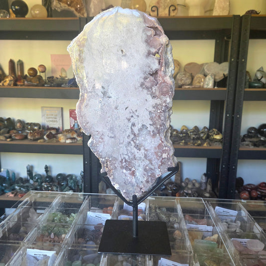 Large crystal on a stand in a store setting with shelves of various items in the background