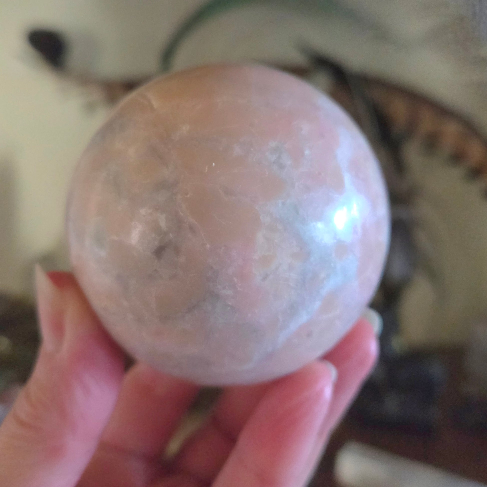 Person holding a translucent pink sphere with a blurred background