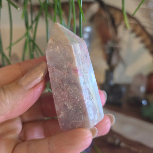 Hand holding a crystal with a blurred indoor background