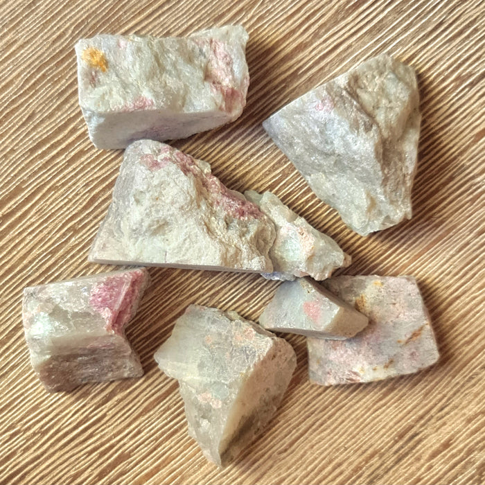 pink and white rough crystal chunk on timber background