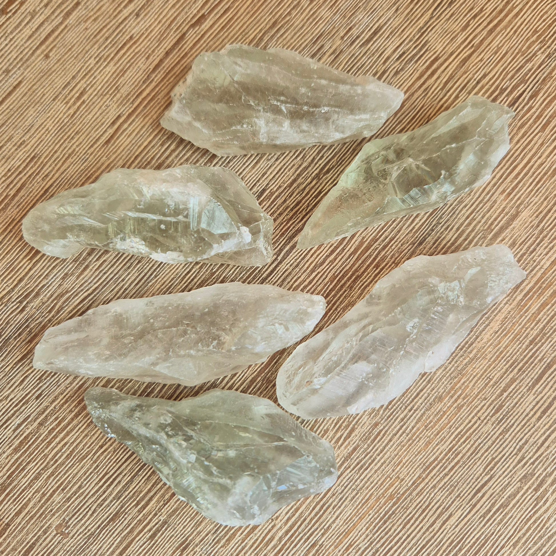 A collection of Prasiolite (Green Amethyst) crystal points scattered on a wooden surface.