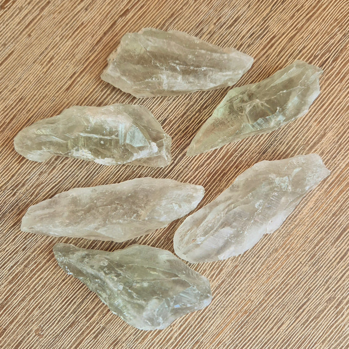 A collection of Prasiolite (Green Amethyst) crystal points scattered on a wooden surface.