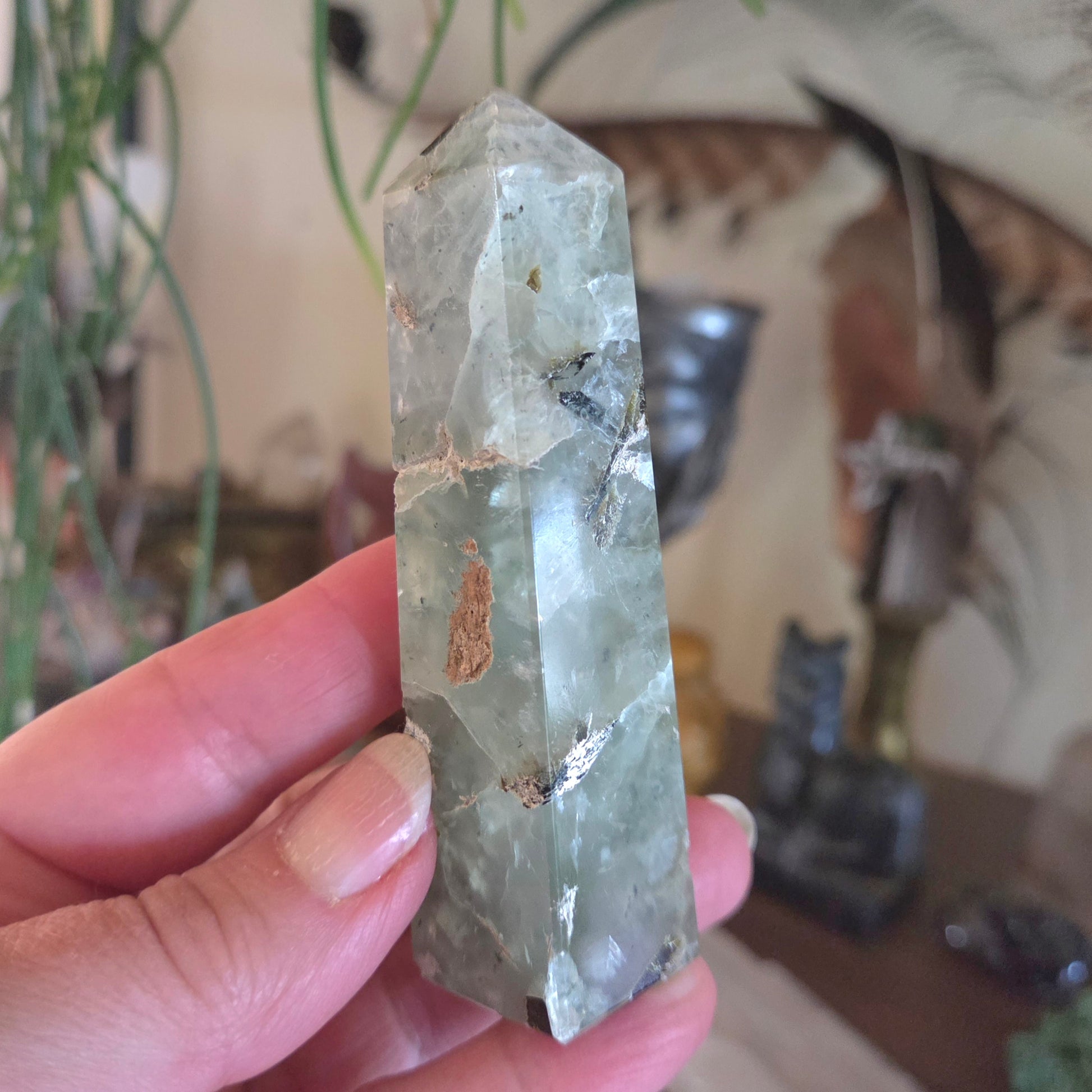 Hand holding a green crystal with a blurred indoor background