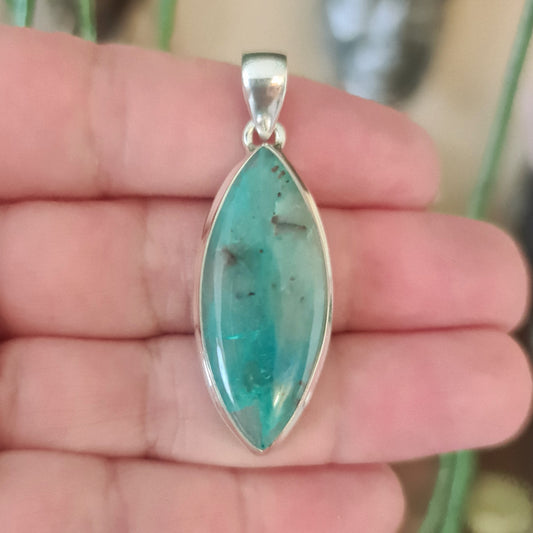 blue elongated crystal pendant held in a hand
