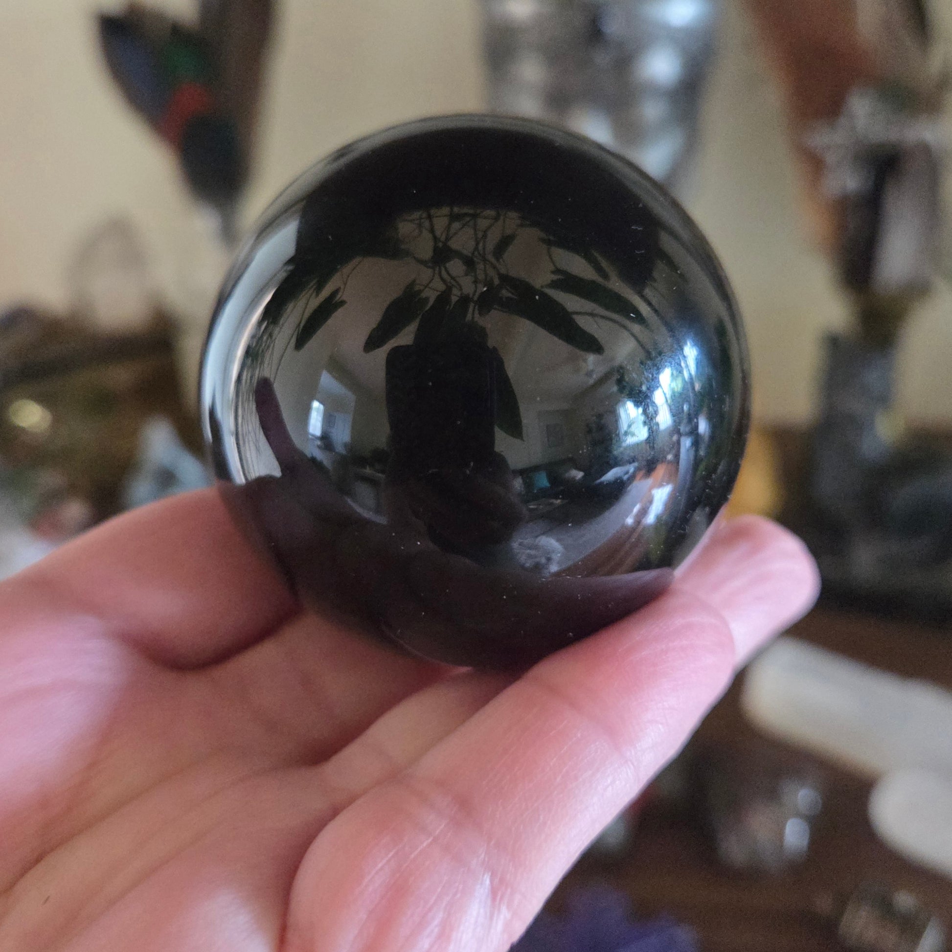 Hand holding a reflective black marble ball with blurred background
