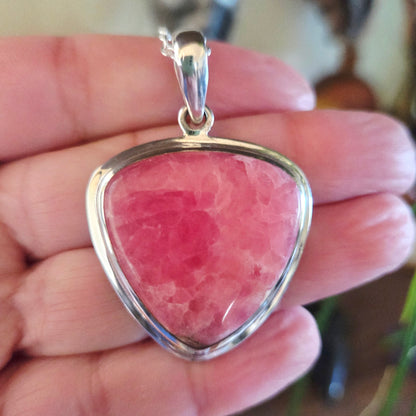 Pink stone pendant with silver frame held in hand