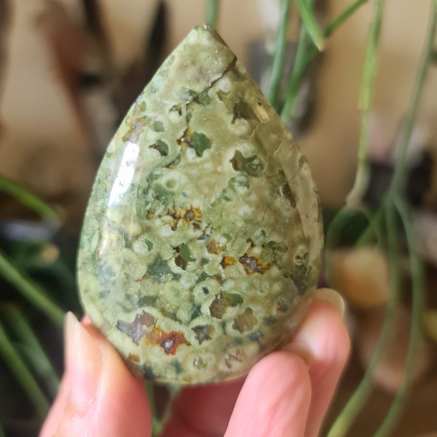green speckled crystal in a aflame design held by a hand